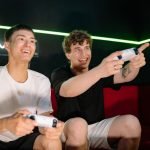 Two young men playing video games indoors, having fun and engaging with controllers. — How to Securely Deposit and Withdraw U