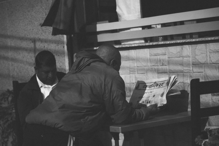 Black and white photo of a man reading a newspaper at an outdoor café in Pokhara, Nepal. — Top crypto casino