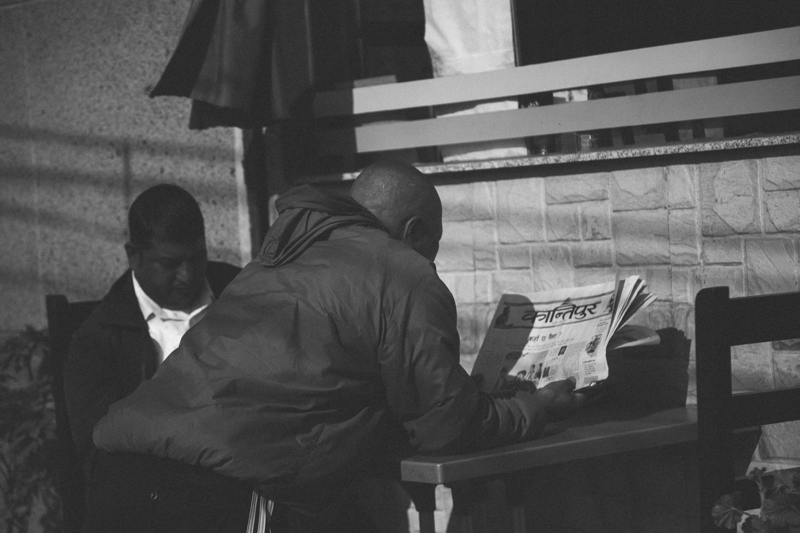 Black and white photo of a man reading a newspaper at an outdoor café in Pokhara, Nepal. — Top crypto casino